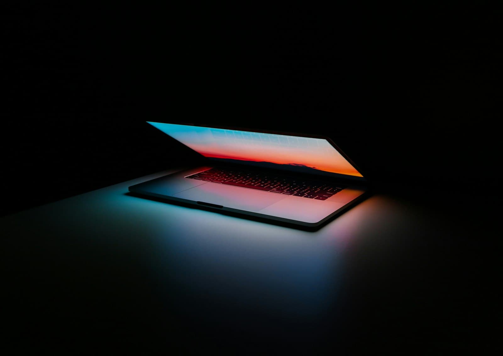 A laptop glowing with warm screen light in a dark room